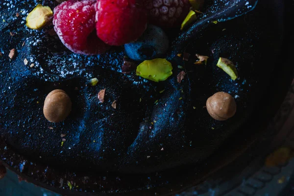 Ahududu, yabanmersini, şam fıstığı ve çikolatalı cheesecake üstü altın çikolata.