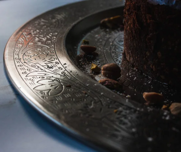 Çikolatalı cheesecake taşıyan metalik bir tabakta parlayan Arapça süslemeler.