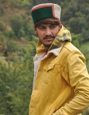 Eli cebinde ve yana bakan yakışıklı bir adam, sarı ceket giyen yakışıklı bir genç ve himachali topi (Himachali geleneksel şapka)) 