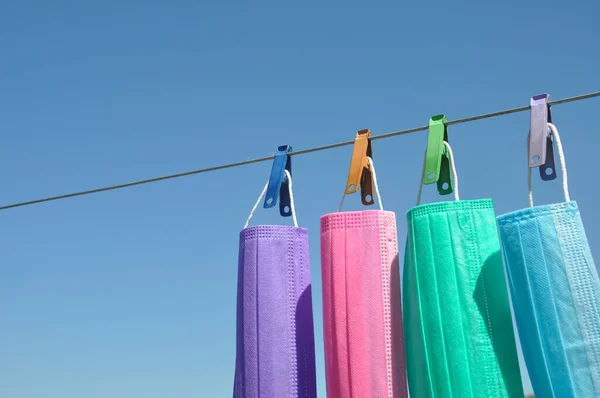 Concept of protect environment from waste and pollution with negative space, Photo of multi colored surgical face mask (Disposable mask) hanging on clothesline wire with clothespin.