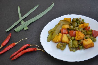 Matar Paneer 'in düz karması sebze tarifi (Hint yemeği) ve kırmızı biberler siyah arkaplanda 