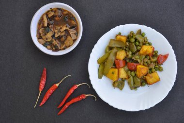 Matar Paneer Sebze ve mantar çorbasının genel görünümü siyah arka planda kırmızı biberli..