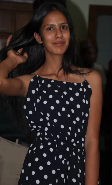 Portrait of a attractive Indian young girl looking at camera with wearing western dress and posing with touching hair