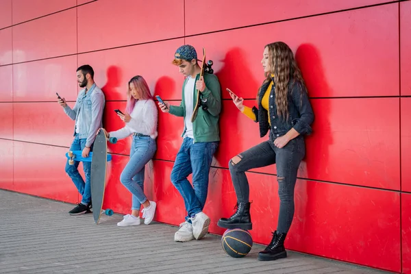 Bir Grup Genç Arkadaş Şehrin Duvarına Yaslanmış Akıllı Cep Telefonları — Stok fotoğraf