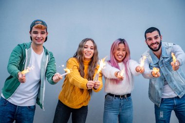 Bir grup çoklu etnik arkadaş maytaplarla oynuyorlar, dört yabancı ellerinde maytaplarla eğleniyorlar.