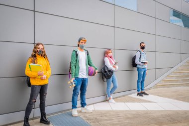 Genç çoklu etnik insanlar sosyal mesafeyi korurken market önünde kuyrukta bekliyorlar -