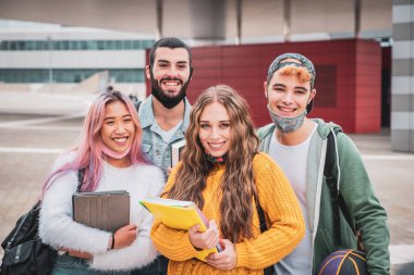 Bir grup genç ya da öğrenci dışarıda gezen ve konuşan sırt çantalı virüs hastalıklarından korunmak için yüz koruyucu maskeler takıyor.