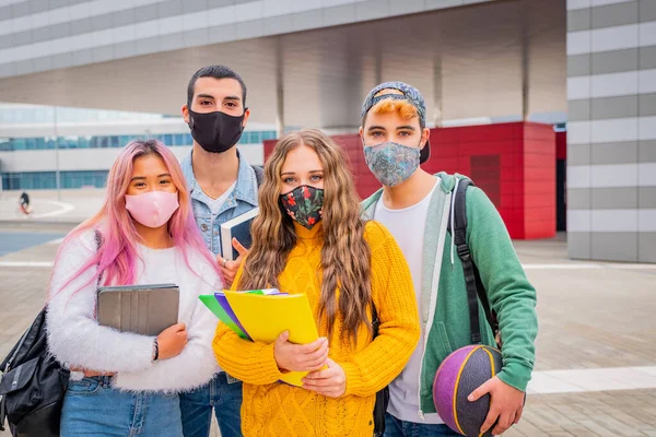 Eğitim, sağlık ve salgın konsepti - Gezen ve konuşan sırt çantalı bir grup üniversite öğrencisi, virüs hastalığından korunmak için yüz koruyucu maskeler takıyor