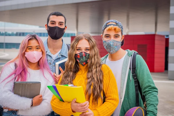 Eğitim, sağlık ve salgın konsepti - Gezen ve konuşan sırt çantalı bir grup üniversite öğrencisi, virüs hastalığından korunmak için yüz koruyucu maskeler takıyor
