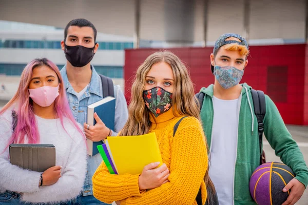 Bir grup genç ya da öğrenci dışarıda gezen ve konuşan sırt çantalı virüs hastalıklarından korunmak için yüz koruyucu maskeler takıyor.