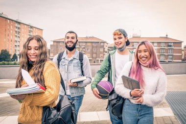 Eğitim, sağlık ve salgın konsepti - Gezen ve konuşan sırt çantalı bir grup üniversite öğrencisi, virüs hastalığından korunmak için yüz koruyucu maskeler takıyor