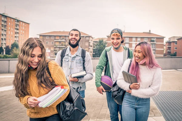 Education, healthcare and pandemic concept - Group of universitary students wearing face protective medical masks for protection from virus disease with backpacks walking and talking outdoors