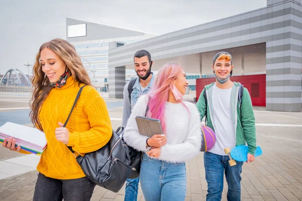 Education, healthcare and pandemic concept - Group of universitary students wearing face protective medical masks for protection from virus disease with backpacks walking and talking outdoors