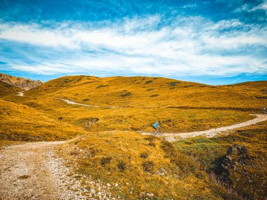 Man going with mountain bike in a mountain route - Young mountain biker riding his e-bike  on a trail going through  meadows - Mountain biking is a fun and challenging sport