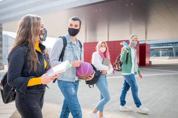 大学のキャンパスでパンデミック時に保護マスクを身に着けて話す顔マスクを持つ多人種間の学生19 コロナウイルスの時間で社会的距離を持つ新しい通常のライフスタイル — ストック写真
