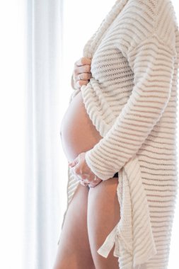 Hamile bir kadın çocuğuna bakarken evde oturuyor. Hamile karnında bebek taşıyan hamile bir anne. Doğum öncesi bakım ve kadın hamileliği konsepti, bebek beklemek. Hamilelik, annelik, hazırlık ve beklenti konsepti