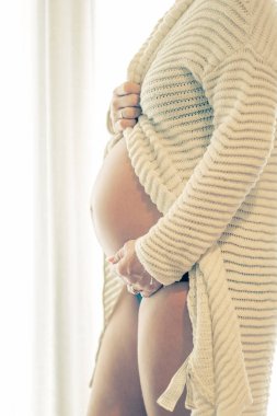 Hamile bir kadın çocuğuna bakarken evde oturuyor. Hamile karnında bebek taşıyan hamile bir anne. Doğum öncesi bakım ve kadın hamileliği konsepti, bebek beklemek. Hamilelik, annelik, hazırlık ve beklenti konsepti