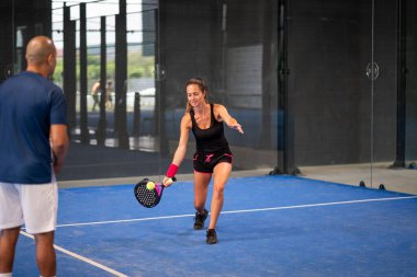 Öğrencisi Padel 'den kadınlara ders verirken gözlemci - Antrenör, genç kıza kapalı tenis kortunda nasıl Padel oynanacağını öğretiyor
