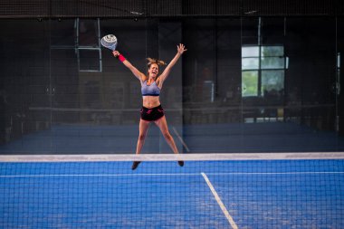 İçerideki padel tenis kortunda sevinen güzel genç bir Wimmer kızının portresi.