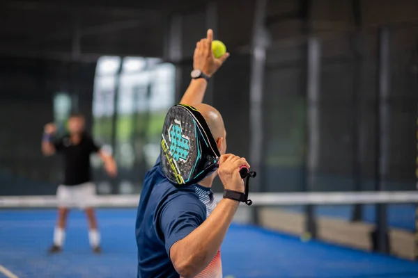 Öğrencisi Padel 'in erkek öğrencisine ders verirken gözlemci çocuğa kapalı tenis kortunda nasıl Padel oynanacağını öğretiyor.