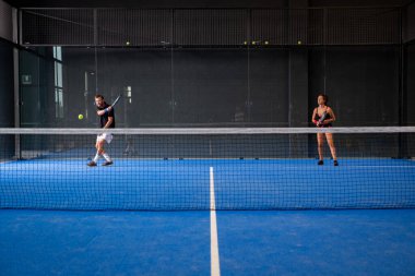 Padel maçları mavi bir çim padel kortunda kalenin arkasında.