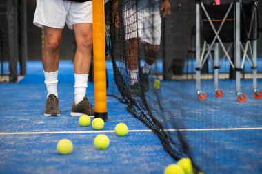 İnsanlar kürek ya da tenis kortunda top topluyor.