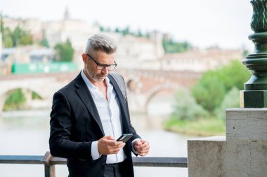 Şehir caddesinde cep telefonu kullanan ve akıllı telefondan mesaj atan bir iş adamı. Genç girişimcinin şehir yaşam tarzı