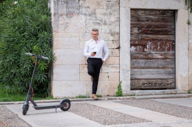 Genç işadamı elektrikli scooter 'ın yanında telefon kullanıyor. Scooter 'a odaklan