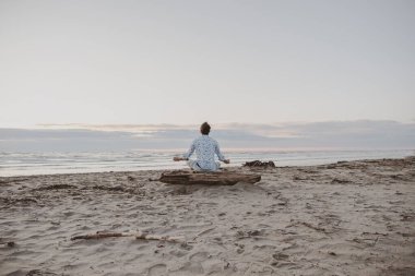 Güneş doğarken deniz kenarında yoga yapan beyaz çocuk, gün batımında plajda meditasyon için yoga yapan adam, yoga konseptiyle sağlıklı.
