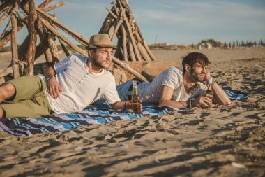 İki genç arkadaş birlikte kumsalda oturup bira içerek ve yaz günbatımında tatilde kadeh kaldırarak vakit geçiriyorlar. Arkadaşlık kavramı