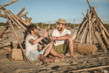 İki genç arkadaş birlikte kumsalda oturup bira içerek ve yaz günbatımında tatilde kadeh kaldırarak vakit geçiriyorlar. Arkadaşlık kavramı