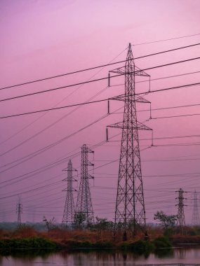 Deniz tuzu tarlasında ve güneş batarken ahırda yüksek voltajlı elektrik hatlarının yansıması.