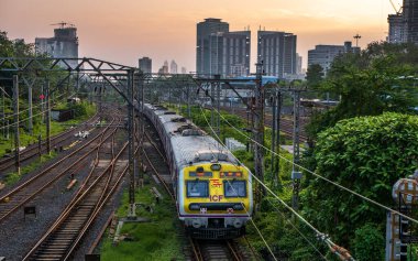 MUMBAI, INDIA - 17 Ekim 2020: Mumbai Suburban Demiryolu, dünyanın en işlek banliyö demiryolu sistemlerinden biri. Günbatımında gökyüzü ile Mumbai Şehri.
