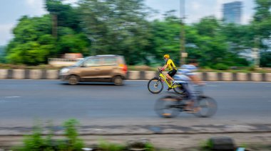 MUMBAI, INDIA - 27 Eylül 2020: Güneşli bir günde COVID-19 / coronavirus salgınının karantinası sırasında Mumbai sokaklarında bisiklet süren insanlar