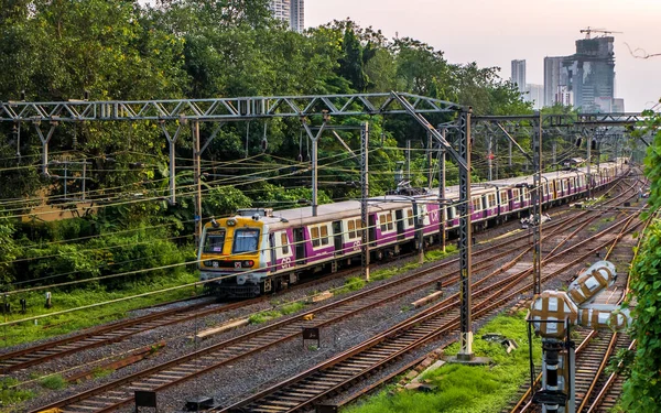 ムンバイ インド 2020年10月17日 世界で最も忙しい通勤鉄道システムの1つであるムンバイ郊外鉄道の高速走行 夕日のムンバイの街並みとスカイライン — ストック写真