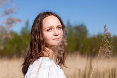 Bahar tarlasında beyaz elbiseli hoş bir kadının portresi.