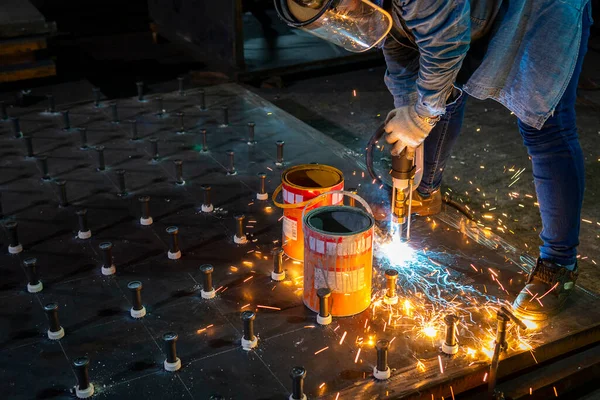 A welder is using a Stud Welding Machine to weld stud bolt on steel plate, at industrial factory.