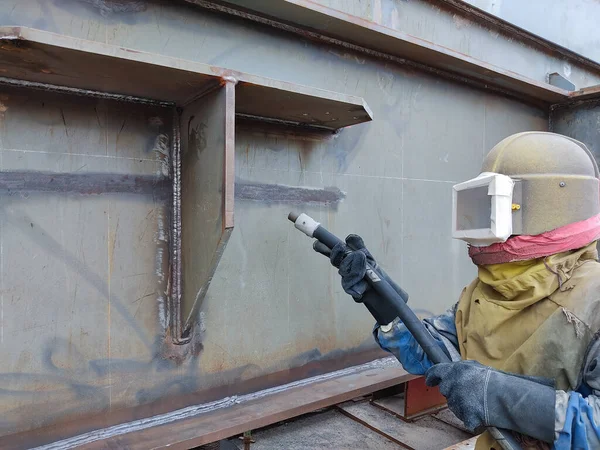 Worker is sandblasting a welding surface and steel structure with pressure blasting pot for create surface profile of steel before painting.