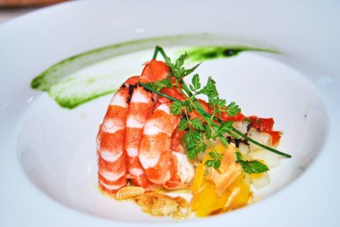 Maydanozla süslenmiş karidesler ve tabakta servis edilen diğerleri.