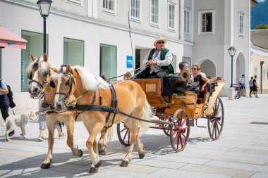 Salzburg, Avusturya - 22 Temmuz 2020: Salzburg sokaklarında at arabası çeken bir çift at. Turistler Salzburg sokaklarında at arabasıyla geziyorlar..