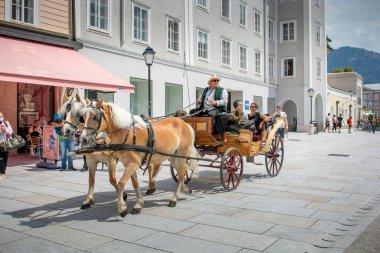 Salzburg, Avusturya - 22 Temmuz 2020: Salzburg sokaklarında at arabası çeken bir çift at. Turistler Salzburg sokaklarında at arabasıyla geziyorlar..