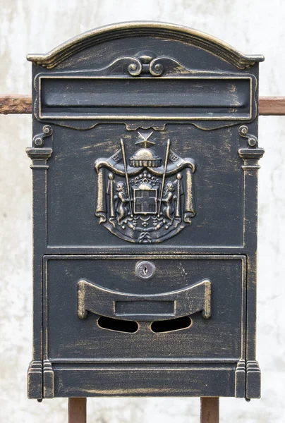 Antique dark letter box or mail drop mounted on the railing. Close up. Detail. Background.