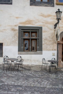 Siyah yuvarlak masalı eski siyah antika pencere ve taş kaldırımda dört metal sandalye. .
