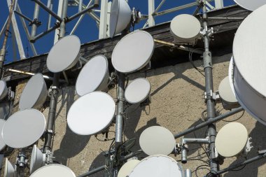 Duvarda uydu iletişim çanakları ve TV radyo vericileri var.