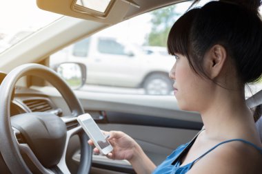 arabanın içinde bir akıllı telefon kullanan kadın