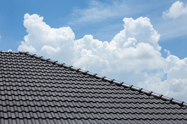 Techo de baldosas negro de la casa con el cielo azul y fondo de nubes —  Fotos de Stock