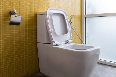 Beyaz floş tuvalet ve sarı duvar mozaik dekorasyon