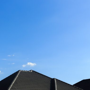 Açık mavi gökyüzü arka plan ile yeni bir ev üzerinde siyah kiremit çatı