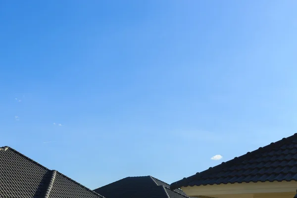 Černá tašek na nový dům s pozadí jasné modré oblohy — Stock fotografie
