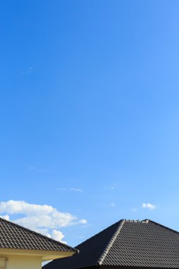 Açık mavi gökyüzü arka plan ile yeni bir ev üzerinde siyah kiremit çatı